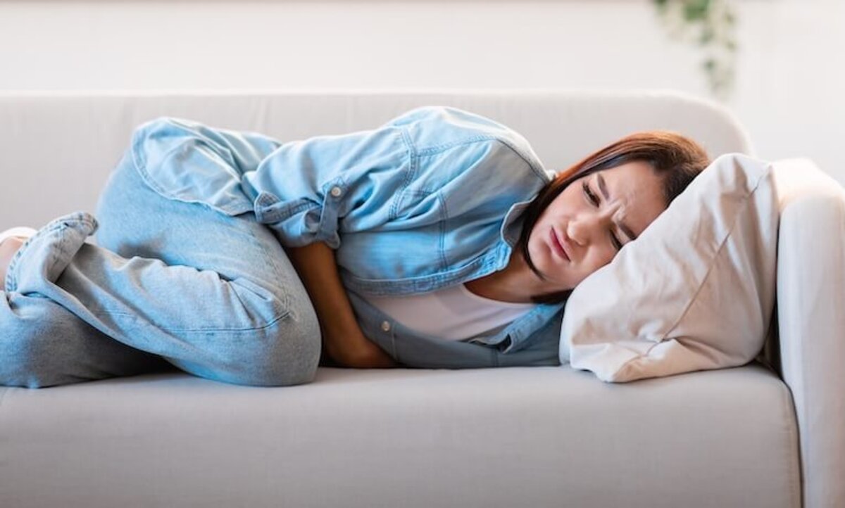 žena ležiaca na sedačke s bolesťou brucha