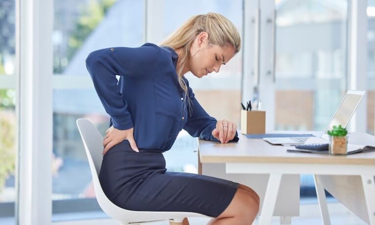 žena pracujúca na notebooku s bolesťou chrbta