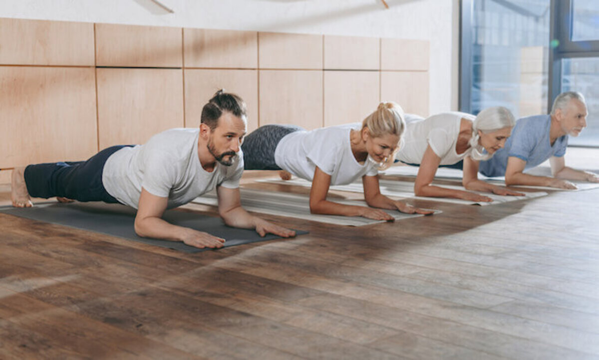 štyria ľudia na karimatkách cvičia pilates