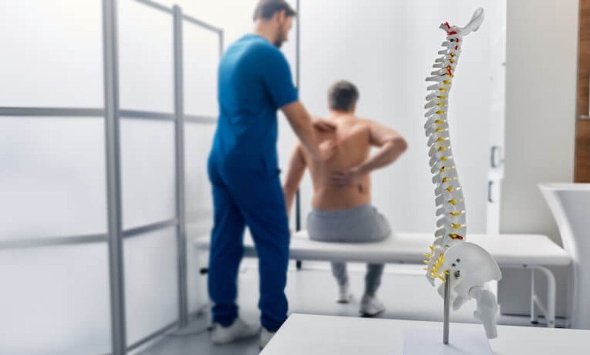 muž s bolesťou chrbta na vyšetrení u fyzioterapeuta