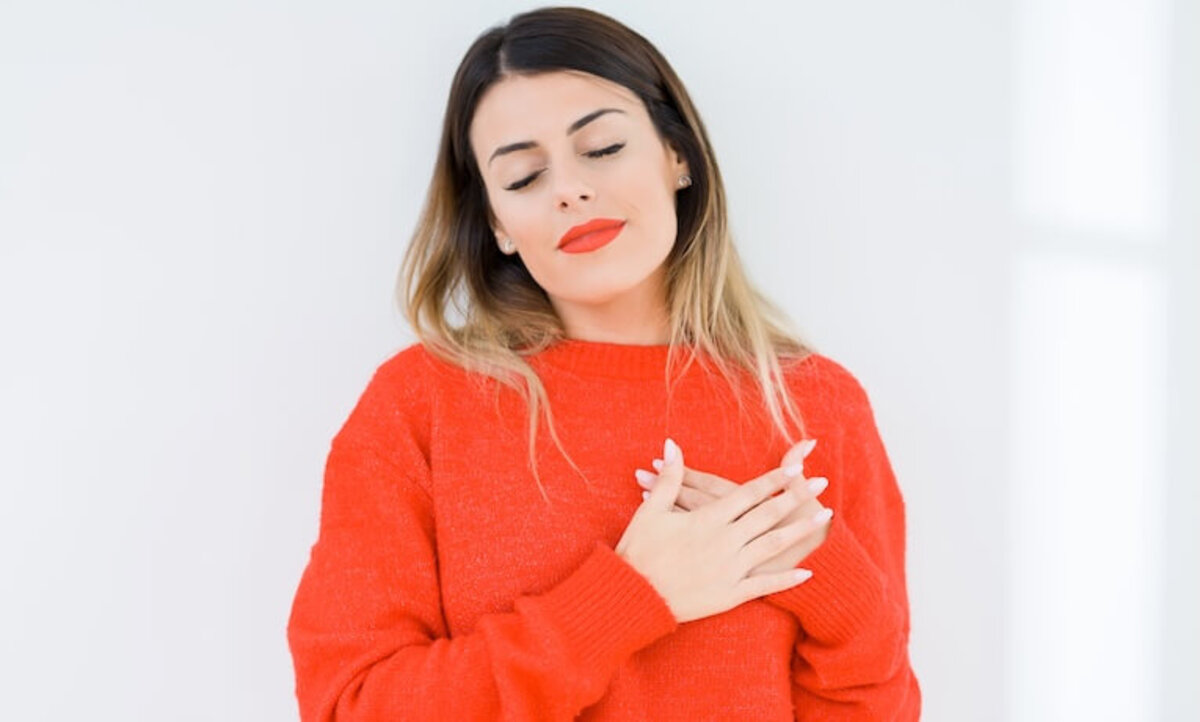 mladá žena so zatvorenými očami si pritláča obe dlane na oblasť srdca