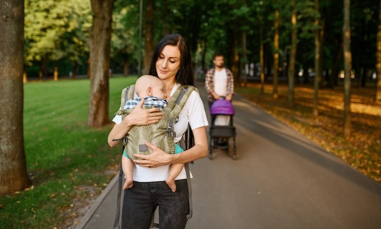 mamička s dieťaťom v nosiči a otecko s kočíkom