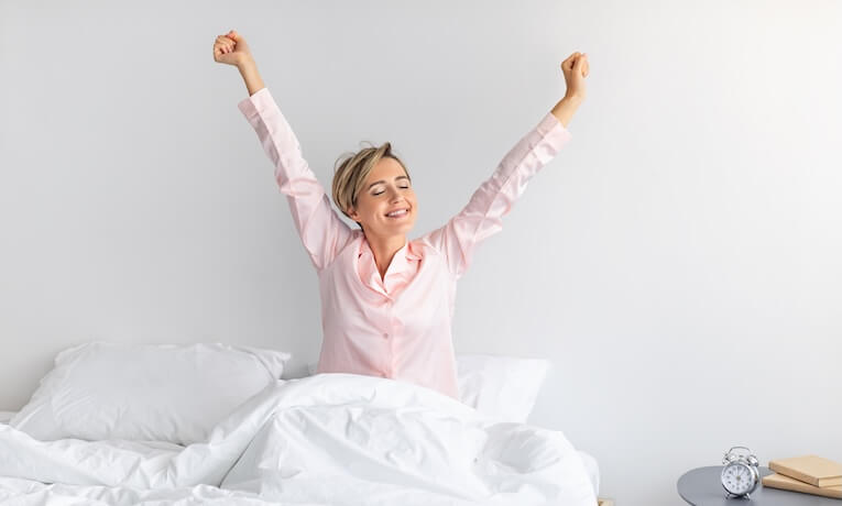 žena sa po spánku naťahuje na posteli