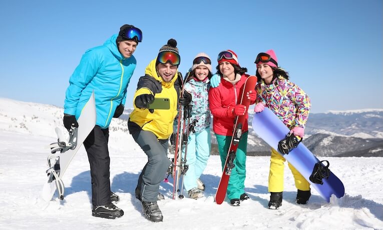 skupina lyžiarov a snowboardistov pózuje pre selfie