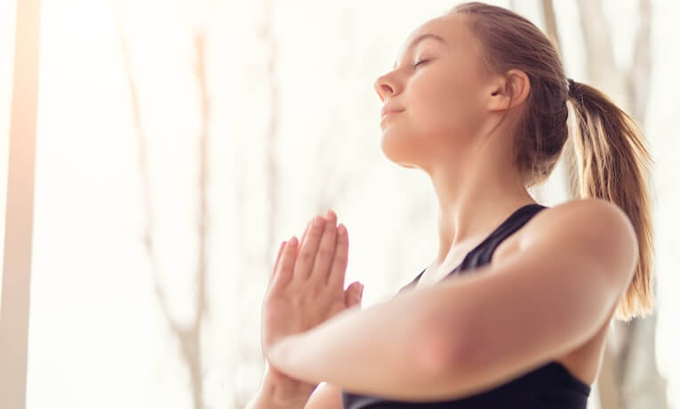 mladá žena so zatvorenými očami a spojenými dlaňami pred hrudníkom