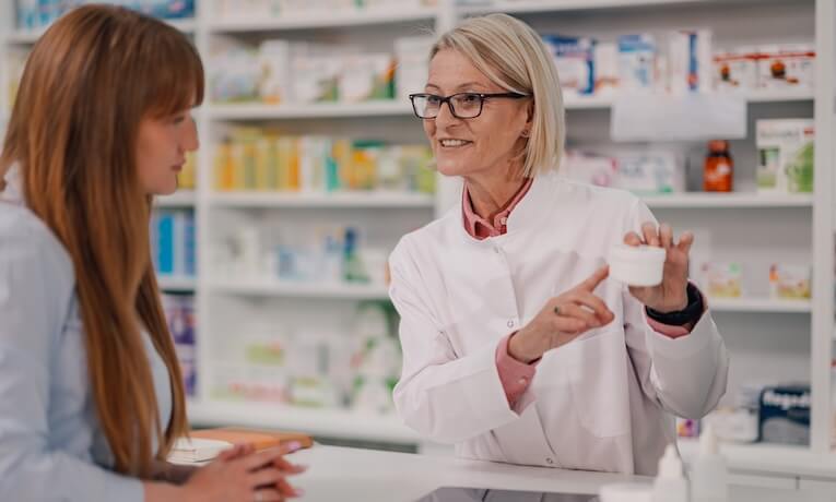 lekárnička ukazuje zákazníčke v lekárni nejaký produkt