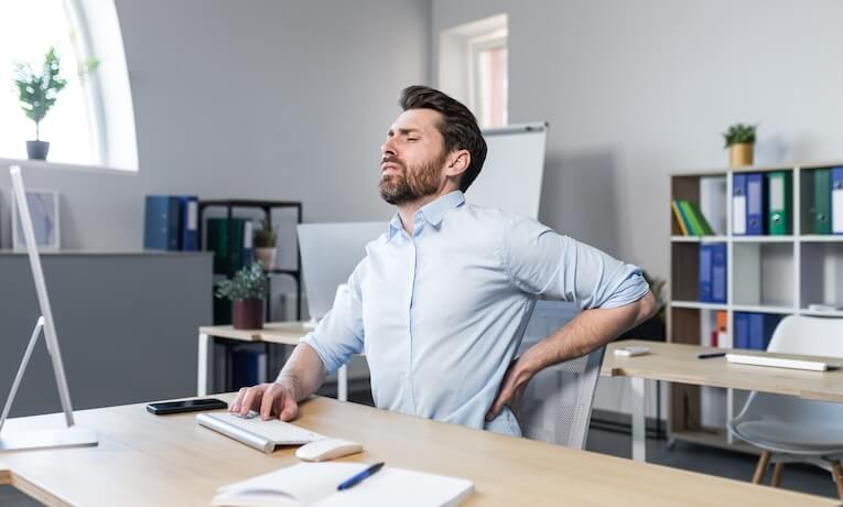 muž pracujúci za počítačom má bolesti v krížoch
