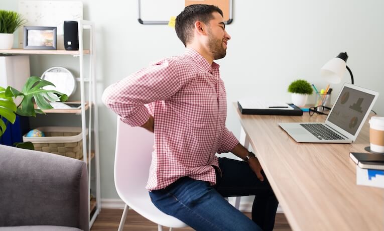 muž pracujúci na notebooku s bolesťou chrbta