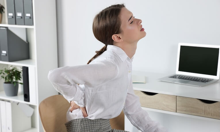 žena na stoličke s bolesťou v krížoch