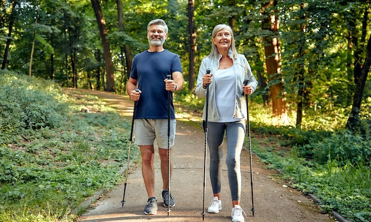 muž a žena v strednom veku praktikujúci nordic walking