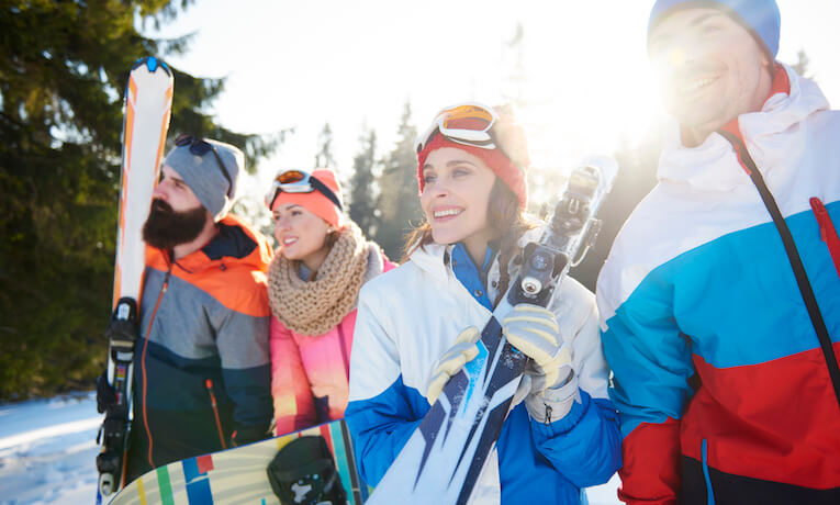 skupina lyžiarov a snowboardistov na kopci