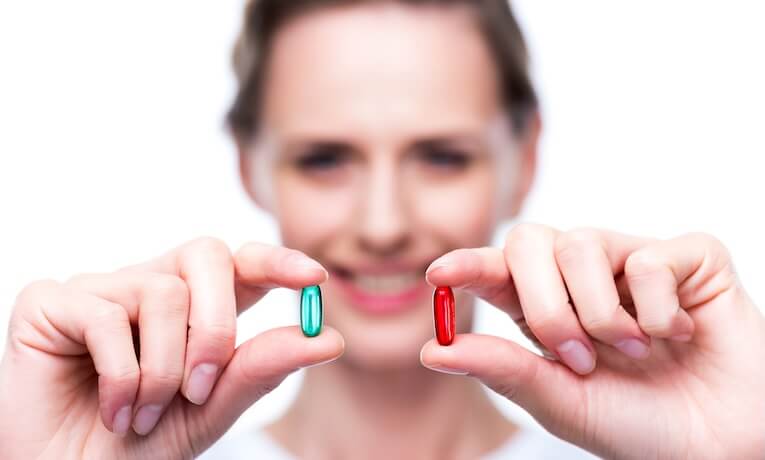 žena ukazuje na kameru dve rôzne kapsule