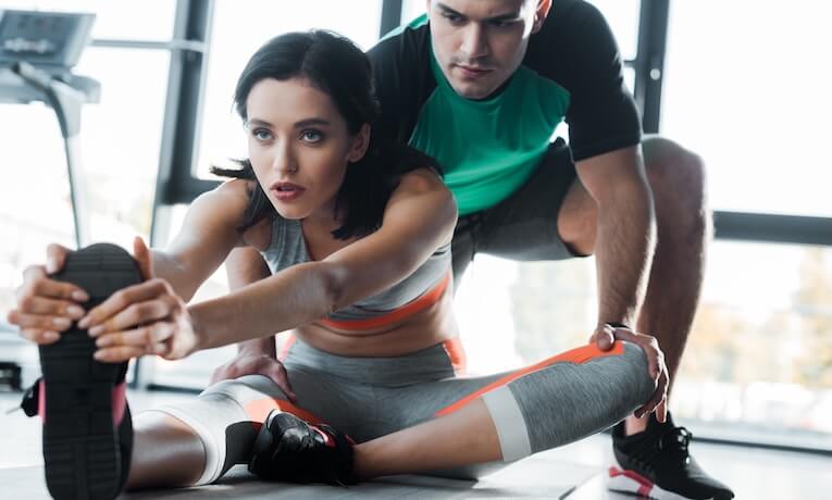 mladá žena cvičí pod dozorom trénera